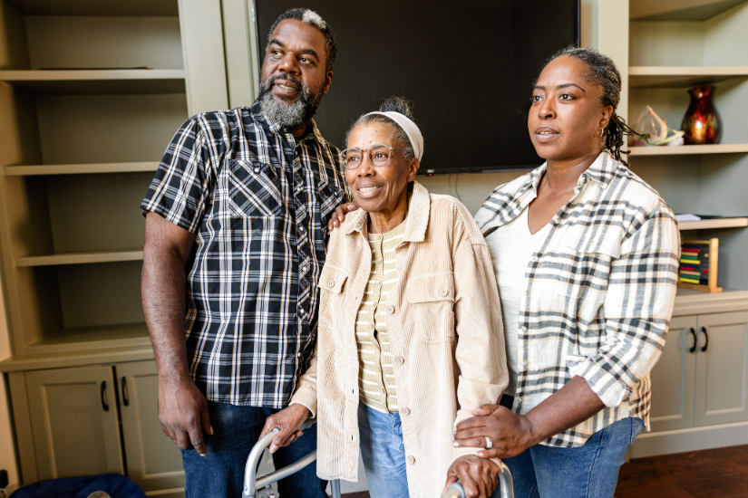 Older mom with a walker standing with her two grown children.