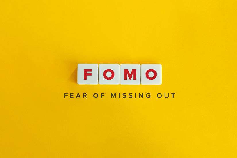 Yellow Background with white cubes with red letters FOMO, below 