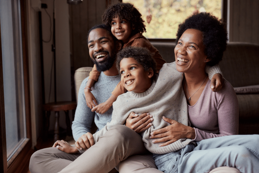 Happy Black parents and their small kids spending time together in the living room.